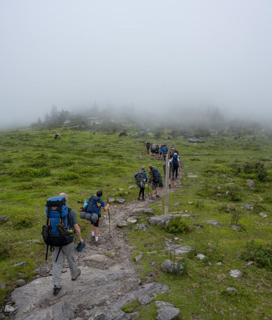 Backpackers hike into the mist.